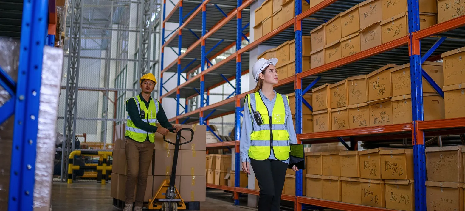 Warehouse workers in safety gear organizing inventory on industrial storage racks.