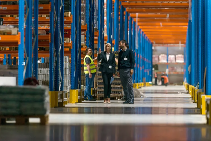 Warehouse management team discussing logistics in a large industrial storage facility.