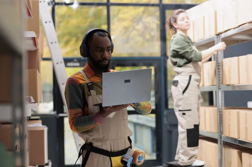 Warehouse worker using a laptop while listening to music.