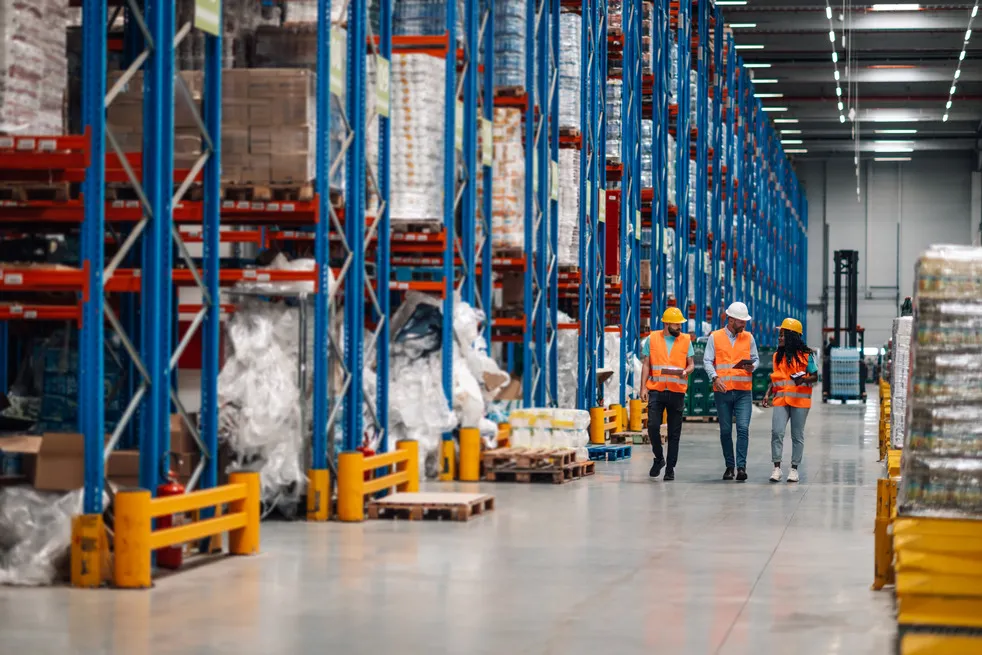 Warehouse workers walking and discussing logistics.